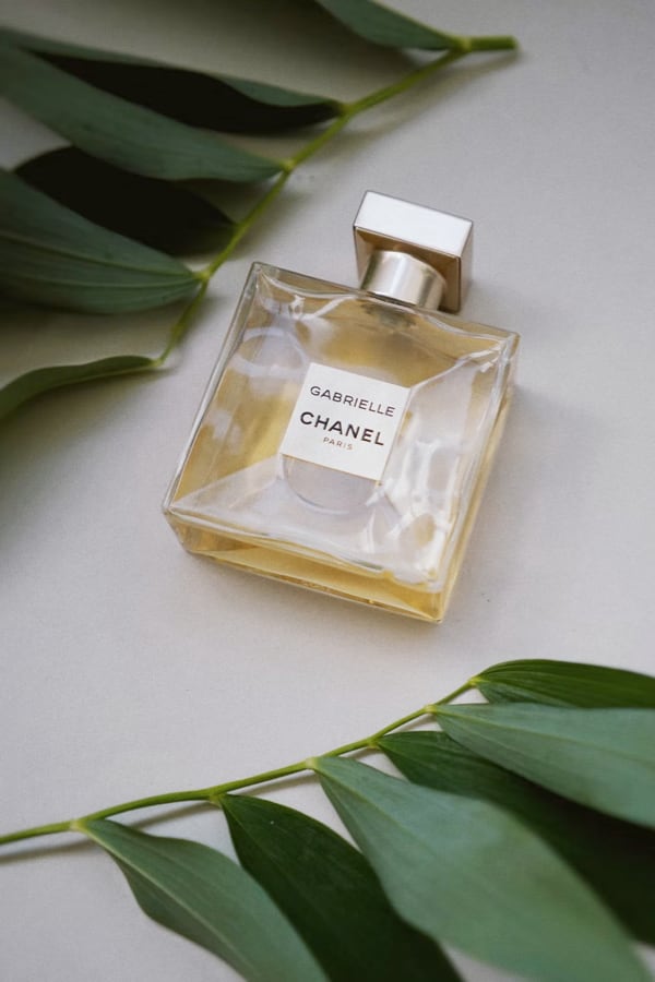 a bottle of perfume surrounded by leaves